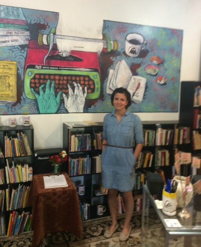 Palabras Libreria/Bookstore Founder and Director Rosie Magana in front of Jeff Slim's mural.